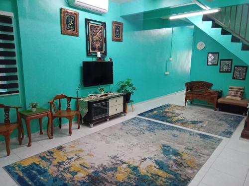 a living room with a tv and a table and chairs at NANIE DAMAI INN in Kluang