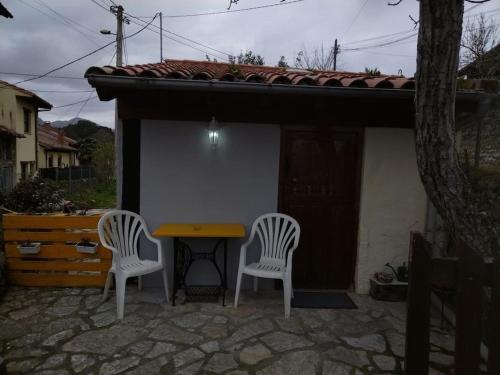 dos sillas y una mesa frente a una casa en La cabañina de zuce, en Parres de Llanes