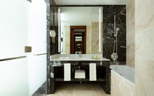 a bathroom with a sink and a tub and a mirror at Hilton Astana in Astana