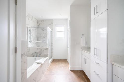 a white bathroom with a tub and a sink at Kitty Faith Barbara by AvantStay 3 Unit Buyout w 12BR in Heart of Nashville in Nashville