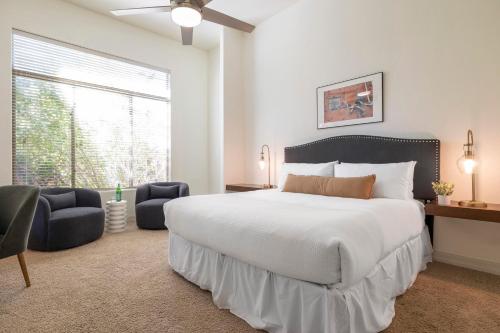 a bedroom with a large white bed and two chairs at Sandflower by AvantStay Oasis w Pool Golf in Phoenix