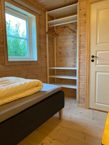 1 dormitorio con cama, ventana y armario en Hytte i landlige omgivelser på Hadeland, en Gran