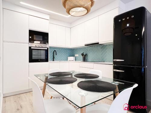 a kitchen with a glass table with chairs and a black refrigerator at La Promenade in Benicàssim
