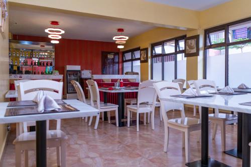 un restaurante con mesas blancas y sillas blancas en Easy Hotel Kenya, en Nairobi