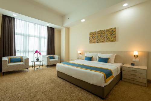 um quarto de hotel com uma cama grande e uma cadeira em Zecon Hotel HPKK em Kuala Lumpur