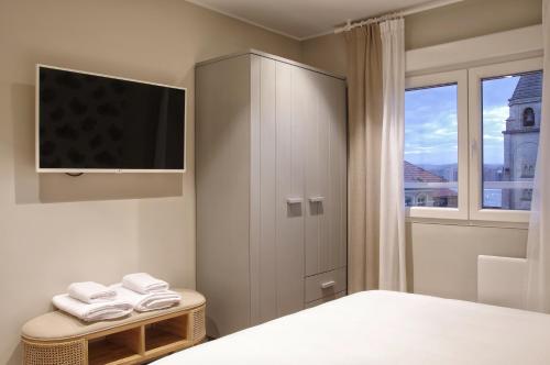 a bedroom with a cabinet with a tv and a window at Apartamentos Bahia San Lorenzo in Gijón