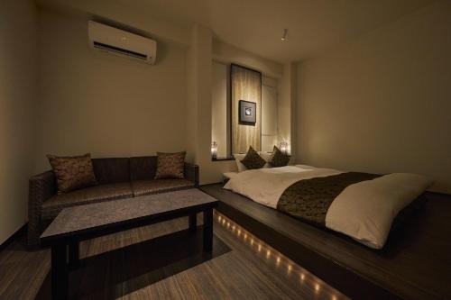 a hotel room with a bed and a couch at SAKE Kura Hotel 川崎宿 in Kawasaki
