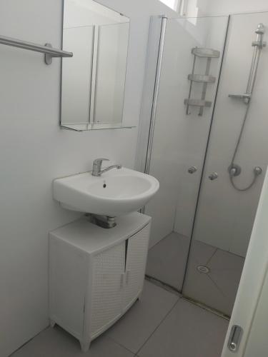 a white bathroom with a sink and a shower at הירקון 10 in Tel Aviv