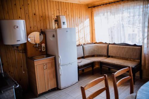 a kitchen with a refrigerator and a table and a bench at Світанок у горах in Verkhniy Yasenov