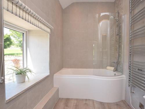 a white bath tub in a bathroom with a window at 3 Bed in Ashford in the Water PK501 in Great Longstone