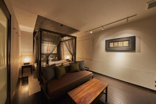 a room with a couch and a bed with a window at SAKE Kura Hotel 川崎宿 in Kawasaki