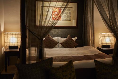a bedroom with a bed with two lamps on tables at SAKE Kura Hotel 川崎宿 in Kawasaki