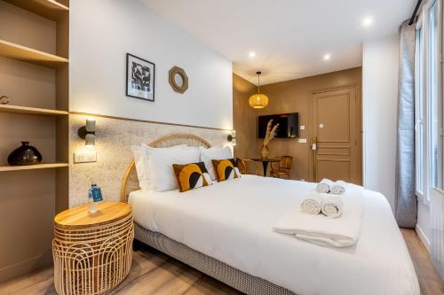 une chambre avec un grand lit blanc et une table dans l'établissement Sweett - Pavillon Madeleine, à Paris