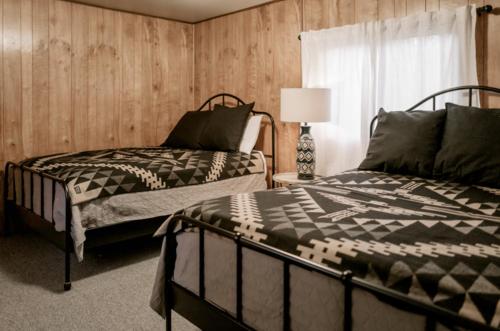 1 Schlafzimmer mit 2 Betten, einer Lampe und einem Fenster in der Unterkunft 2403 - Oak Knoll #4 cabin in Big Bear Lake