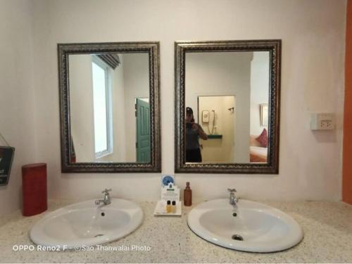 two sinks in a bathroom with two mirrors at Meet The Sea in Khlong Yai