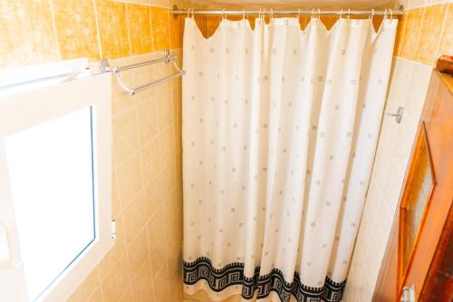 uma cortina de chuveiro numa casa de banho ao lado de uma janela em Smarula Villa em Firostefani