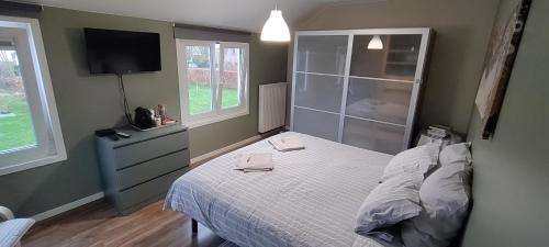 a bedroom with a bed and a flat screen tv at Au Fond des Rys in Grez-Doiceau