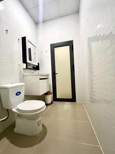 a white bathroom with a toilet and a door at Phuong Nam Sa Đec Hotel in Ấp Phú Thuận (1)