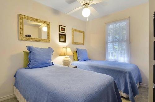 2 camas azules en una habitación con espejo en Lavender Jungle by AvantStay Great Location w Patio Shared Pool Week Long Stays Only, en Key West