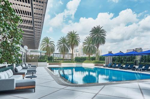 a pool on the rooftop of a building with chairs and palm trees at Novotel Singapore on Kitchener in Singapore