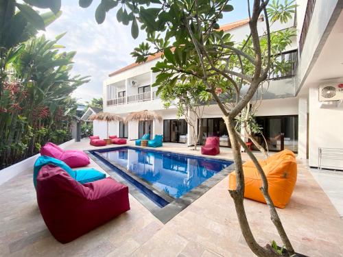 an outdoor swimming pool with colorful chairs and a house at Hotel Summer Of Surf in Ungasan