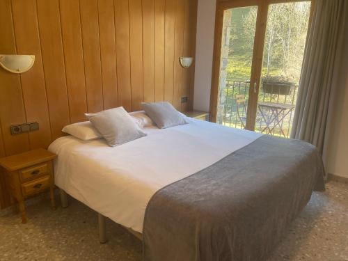 Schlafzimmer mit einem großen Bett und einem Fenster in der Unterkunft Hostal El Quintà in Espinavell