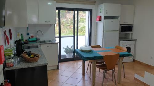 uma cozinha com uma mesa e cadeiras numa cozinha em A Caminho da Ilha em Ponta Delgada