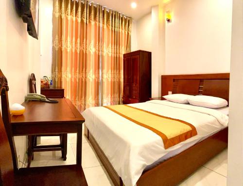 a bedroom with a bed and a table and a desk at Phuong Nam Sa Đec Hotel in Ấp Phú Thuận (1)