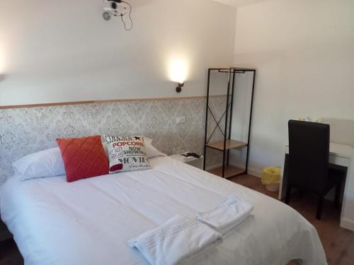 a bedroom with a bed with white sheets and a lamp at SG ROOMS in Consuegra