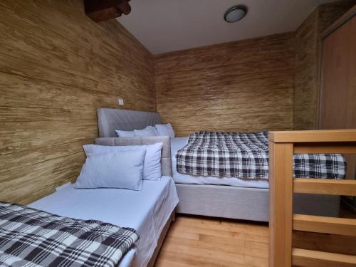 two beds in a small room with wooden walls at Apartman Lord Aparthotel Vučko in Jahorina