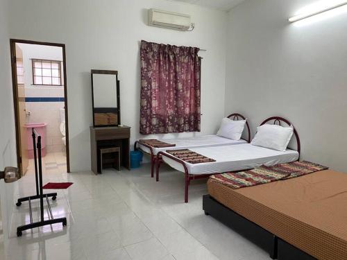 a bedroom with two beds and a mirror and a window at Go Holiday Taiping Homestay in Simpang