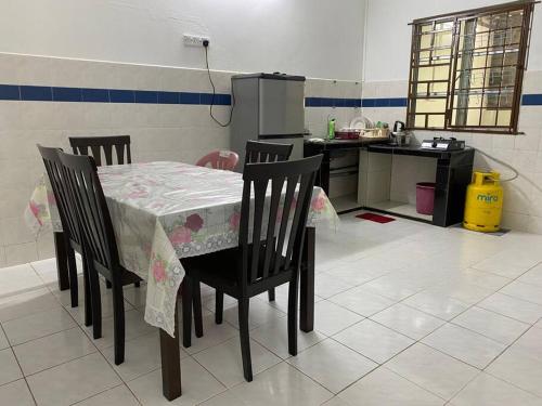 uma cozinha com uma mesa com 4 cadeiras e uma cozinha com um frigorífico em Go Holiday Taiping Homestay em Simpang