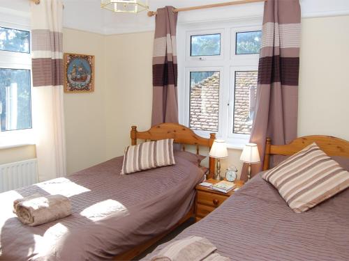 1 dormitorio con 2 camas y 2 ventanas en 4 Bed in Studland DC046 en Studland