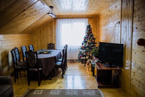 a dining room with a christmas tree and a table at Світанок у горах in Verkhniy Yasenov