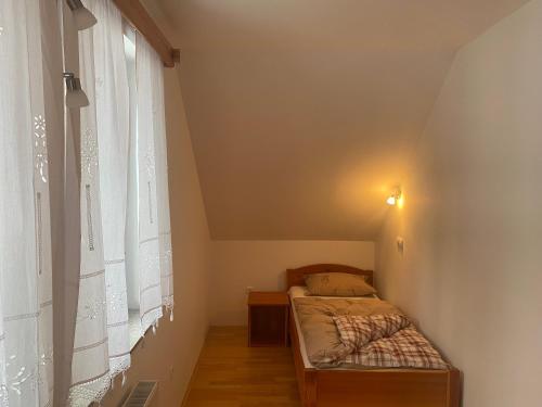 a small bedroom with a bed and a window at Rooms Kočna in Zgornje Jezersko