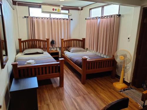 a bedroom with two beds and a fan in it at Baan Mai Muang Nan in Nan