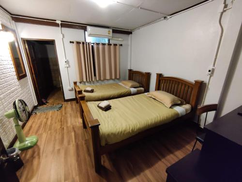 a room with two beds and a lamp in it at Baan Mai Muang Nan in Nan