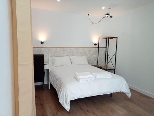 1 dormitorio con cama blanca y escritorio en SG ROOMS, en Consuegra