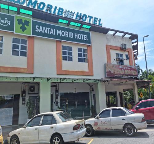 dois carros estacionados em frente a um hotel em OYO 90901 Santai Morib Hotel em Banting