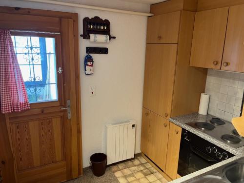 eine Küche mit einer Tür, einem Fenster und einem Waschbecken in der Unterkunft Chalet Baur in Arosa