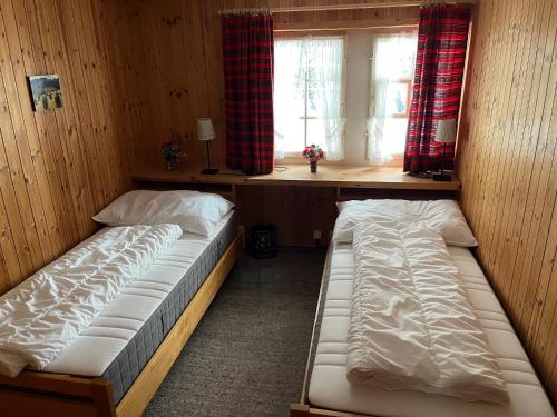 two beds in a room with a window at Chalet Baur in Arosa