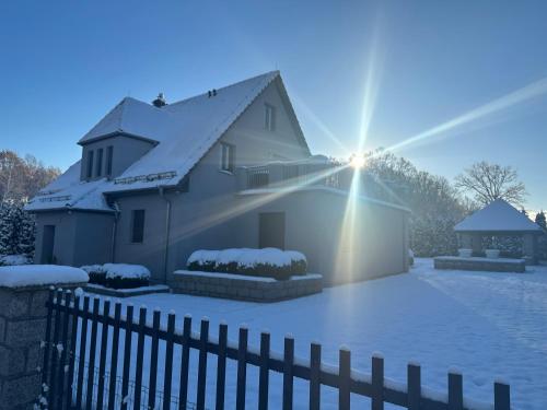 een huis bedekt met sneeuw met de zon erachter bij Villa Coco in Gryfów Śląski