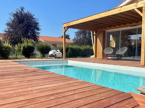 une piscine avec une terrasse en bois à côté d'une maison dans l'établissement Maison avec piscine et jardin privatifs - un séjour au calme, à Biscarrosse
