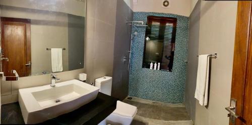 La salle de bains est pourvue d'un lavabo, de toilettes et d'un miroir. dans l'établissement Spacious luxury room with beautiful views !, à Kolonnawa