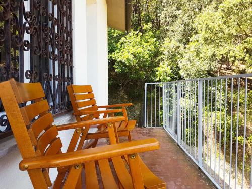 Villa ai Pini di ArgonautiVacanze في بروكيو: كرسيين خشبيين جالسين على شرفة مع سياج