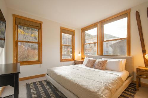 a bedroom with a bed and a desk and windows at Sugarloaf by AvantStay Telluride Home In Great Location Near the Slopes in Telluride