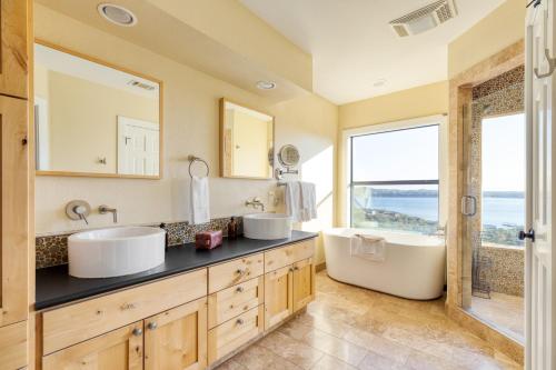 La salle de bains est pourvue de 2 lavabos, d'une baignoire et d'une fenêtre. dans l'établissement Dawson by AvantStay Serene Austin Home set Amongst nature w Pool Hot Tub Close to Lake Travis, à Austin