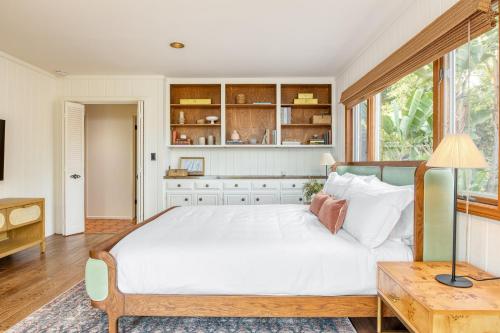 a bedroom with a large white bed and a table at Dume Point by AvantStay Tennis Pool in Malibu in Malibu