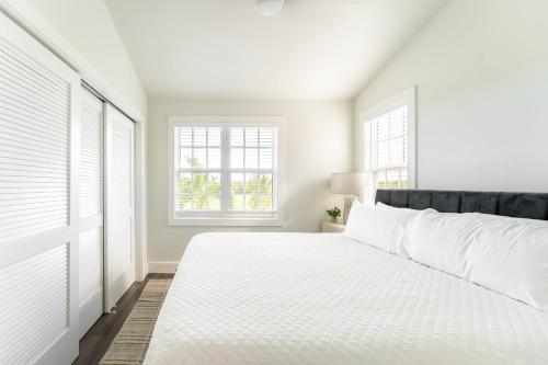 a white bedroom with a bed and two windows at Paradise Point by AvantStay Golf Course Living in Stock Island