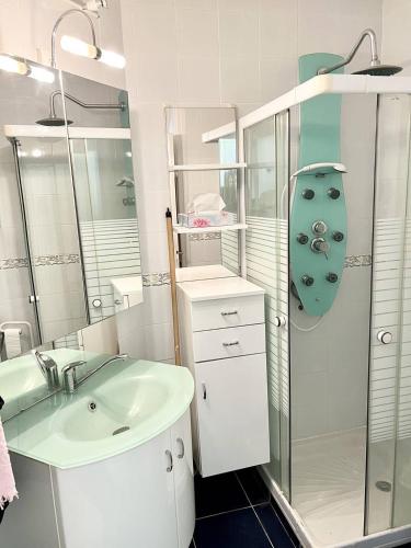 une salle de bain blanche avec un lavabo et une douche dans l'établissement STUDIO CLIMATISE 3 PERSONNES A PROXIMITE IMMEDIATE MER ET PLAGE, au Grau-du-Roi